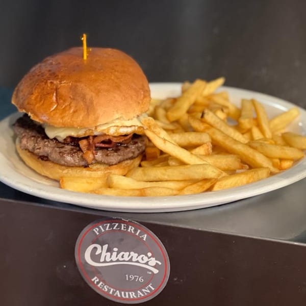 A Chiaro's burger with cheese, bacon, and a fried egg, served with a side of fries.