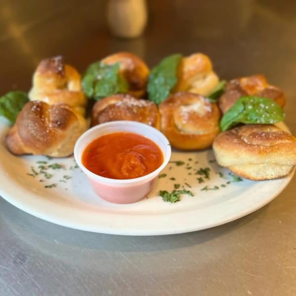 Garlic knots with fresh basil and parmesan cheese, served with a side of marinara sauce.