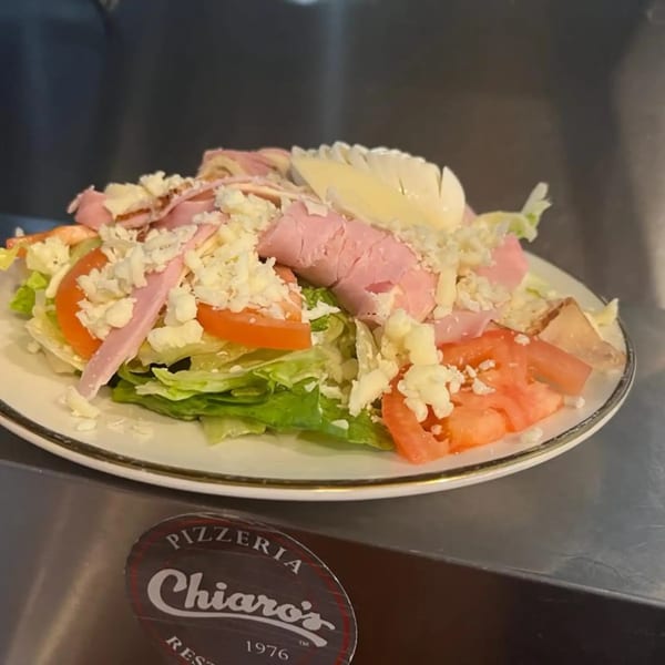 A fresh salad with lettuce, tomatoes, ham, cheese, and a hard-boiled egg from Chiaro's Pizzeria.